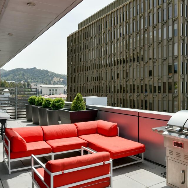 One-Bedroom Luxury Apartments In Berkeley, CA - Berkeley Central - BBQ Area With Grill, Couch Seating, Ping Pong Table, And City Views