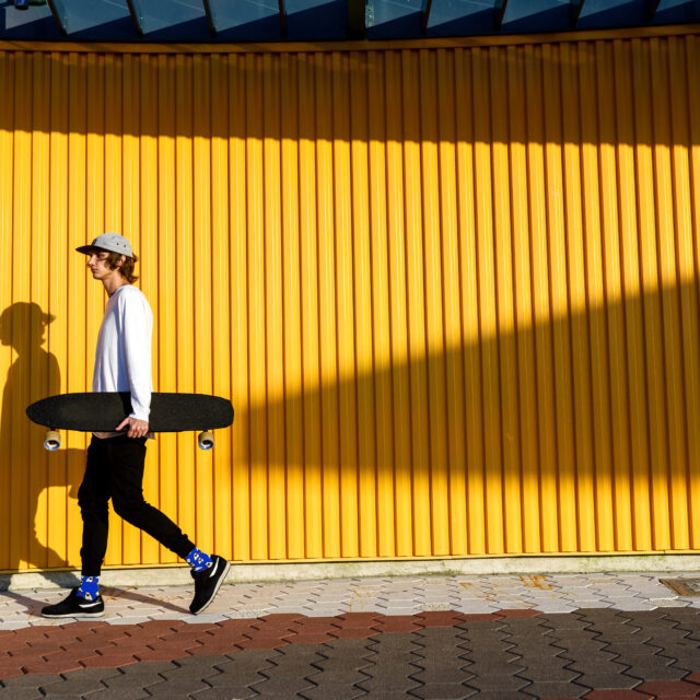 브루클린 해변 산책로에서 롱보드를 타는 젊은 힙스터 소년